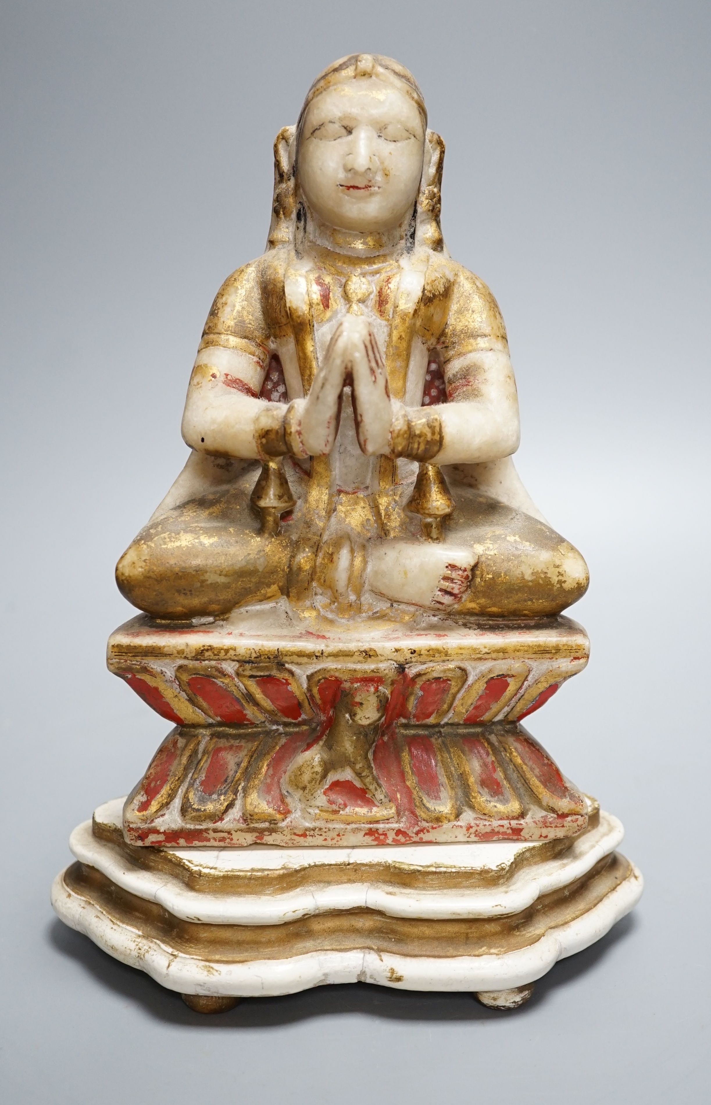 A late 19th century Indian carved alabaster seated figure, on associated wooden stand, 26cm